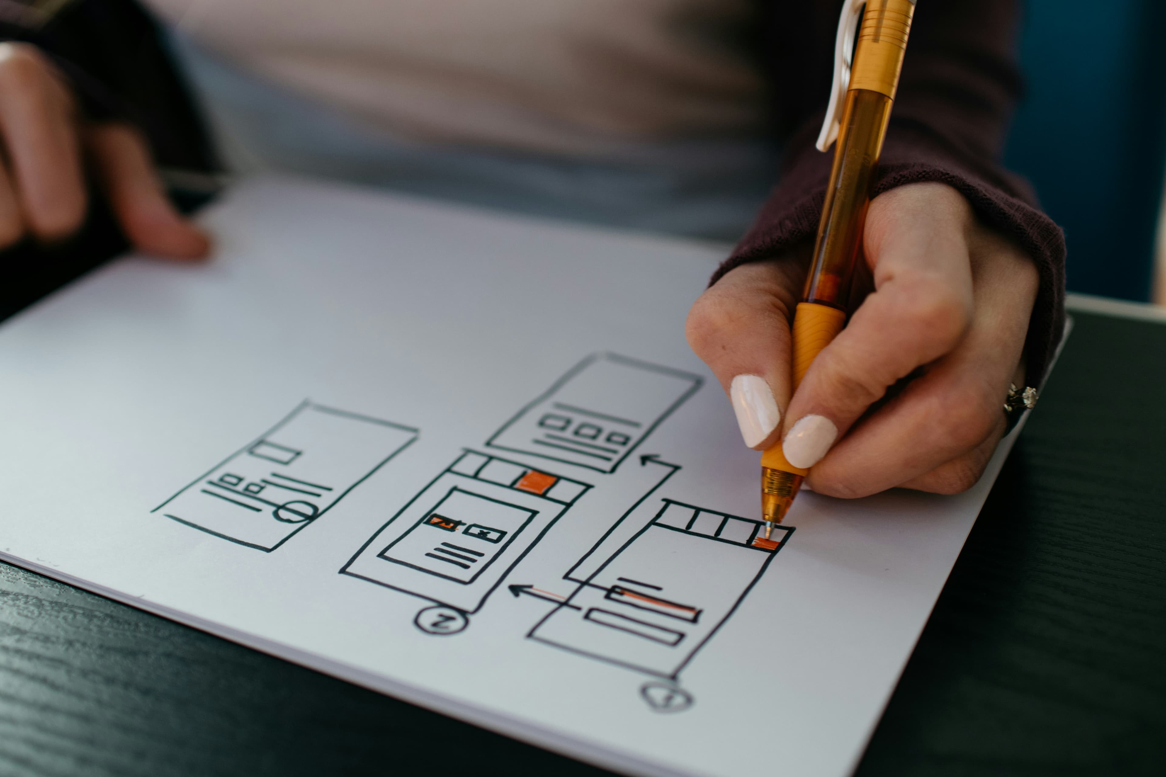Hand sketching wireframes and user interface designs on paper